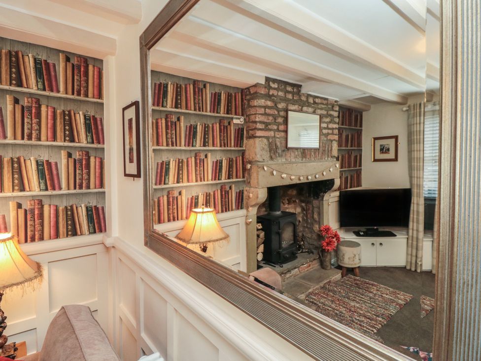 A living room with a fireplace and bookshelves at Dove Cottage in Pickering