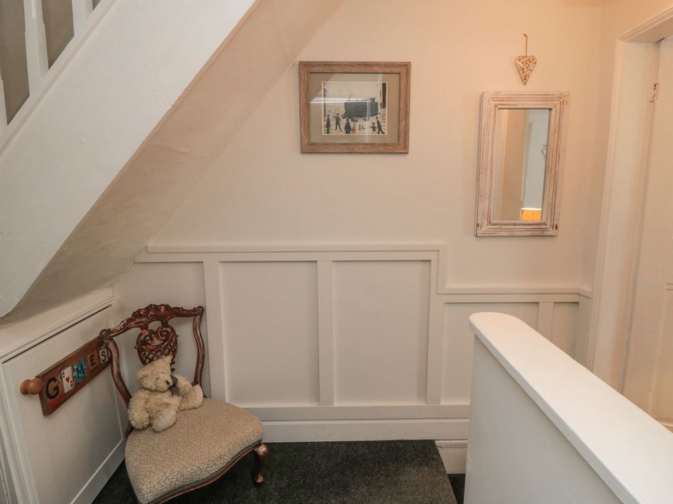 A hallway with a chair and framed pictures at Dove Cottage in Pickering
