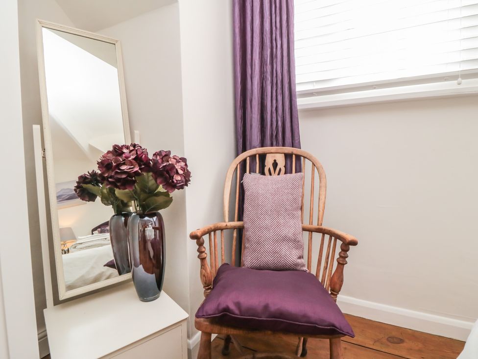 A chair with a pillow and flowers on a vase in the bedroom at Dove Cottage in Pickering