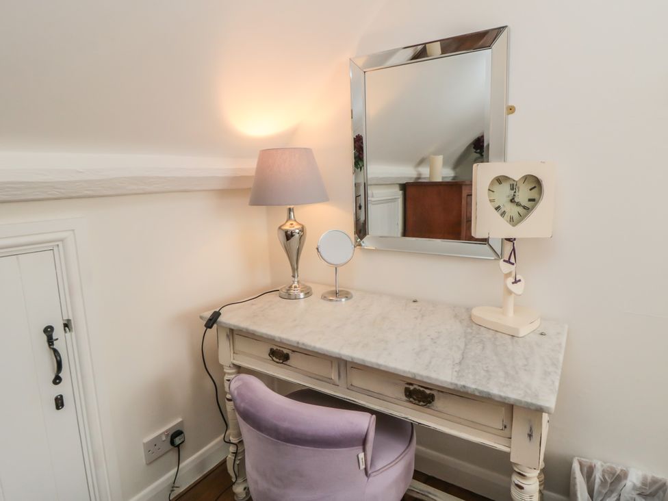 A vanity table with a mirror and lamp in a bedroom at Dove Cottage in Pickering