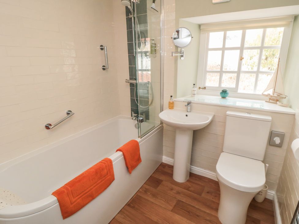 A bathroom with a bathtub, shower, toilet, and sink at Dove Cottage in Pickering