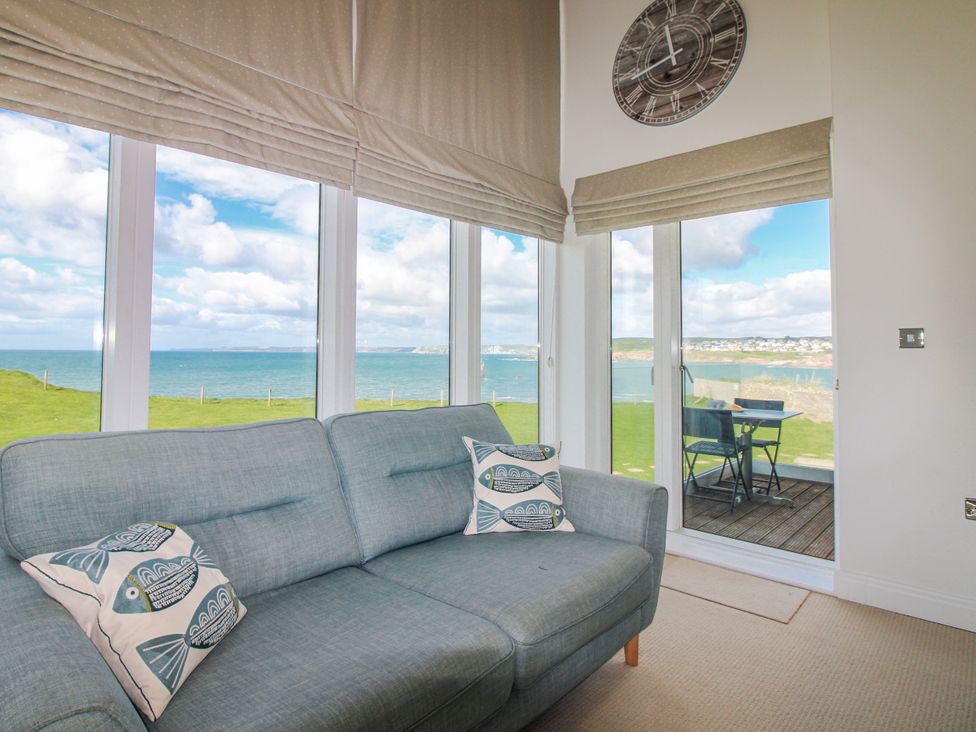 A living room with a sofa and windows overlooking the sea at 7 Ocean's Edge in Thurlestone
