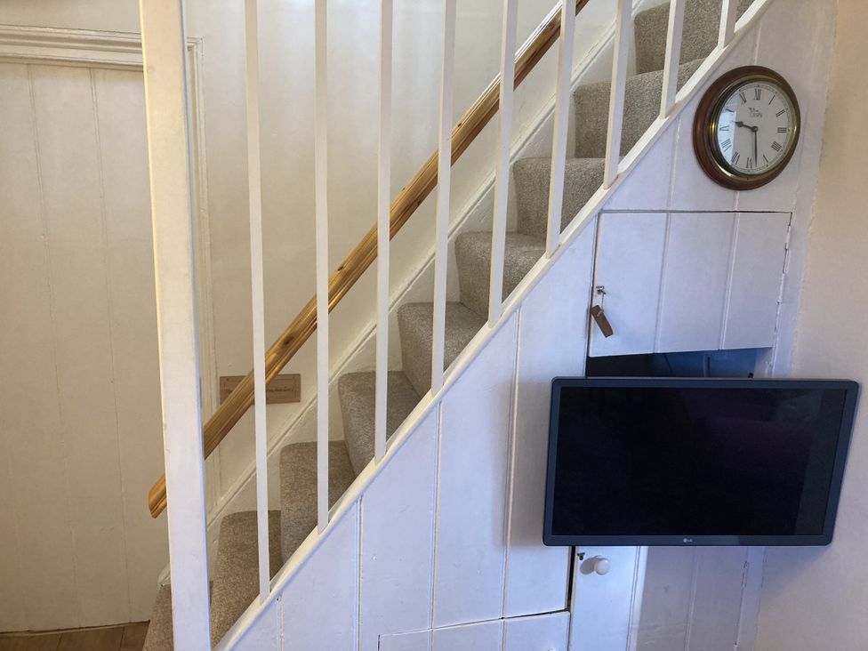 A staircase with a clock and television at Yew Tree Cottage Stoke Fleming