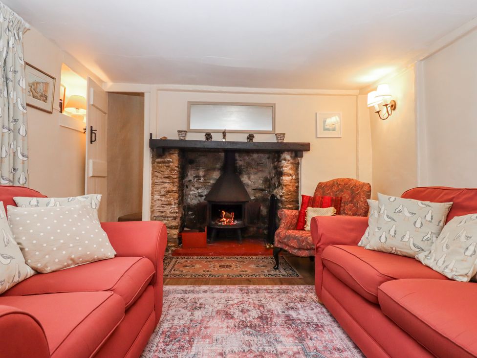 A living room with a fireplace and two sofas at Yew Tree Cottage in Stoke Fleming
