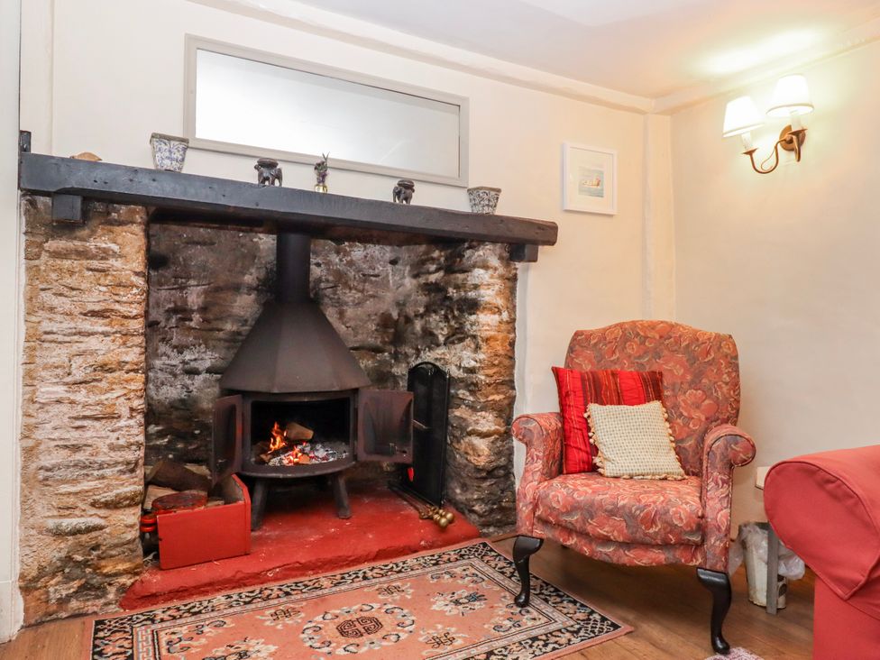 A living room with a fireplace and armchair at Yew Tree Cottage in Stoke Fleming