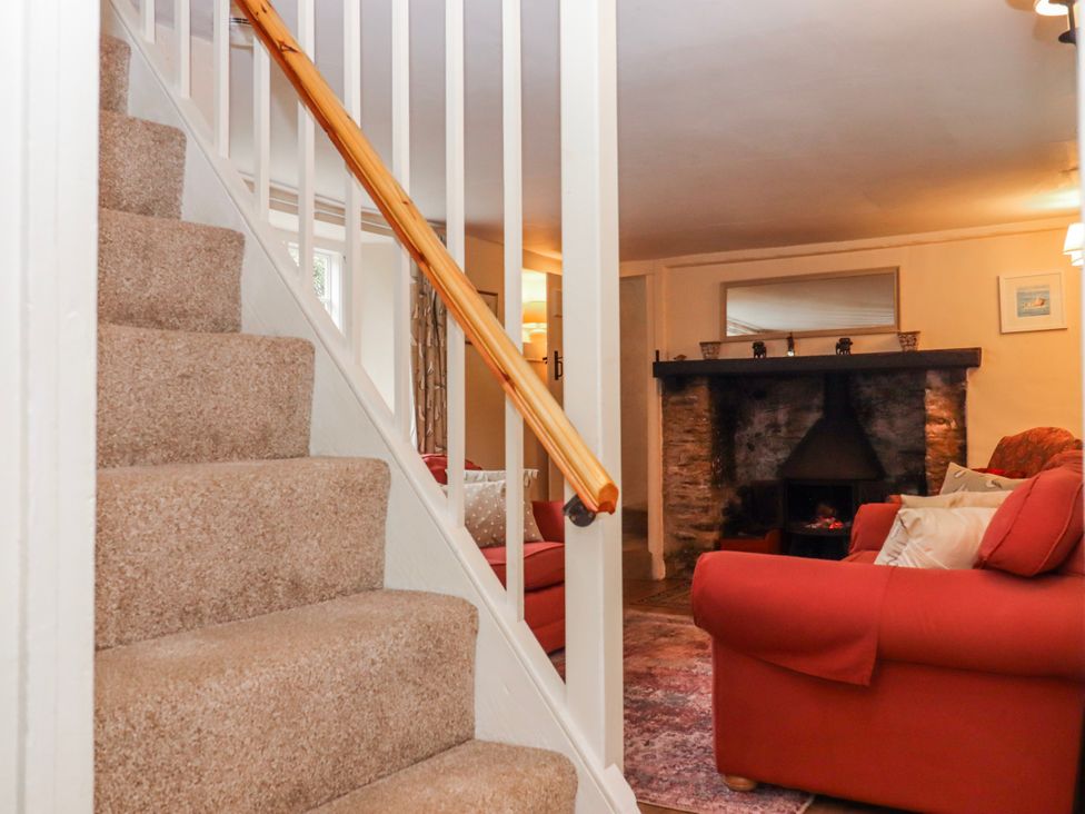 A living room with a fireplace and sofa at Yew Tree Cottage Stoke Fleming