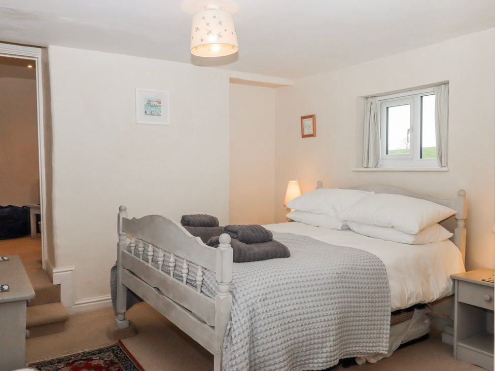 A bedroom with a bed and nightstand at Yew Tree Cottage in Stoke Fleming