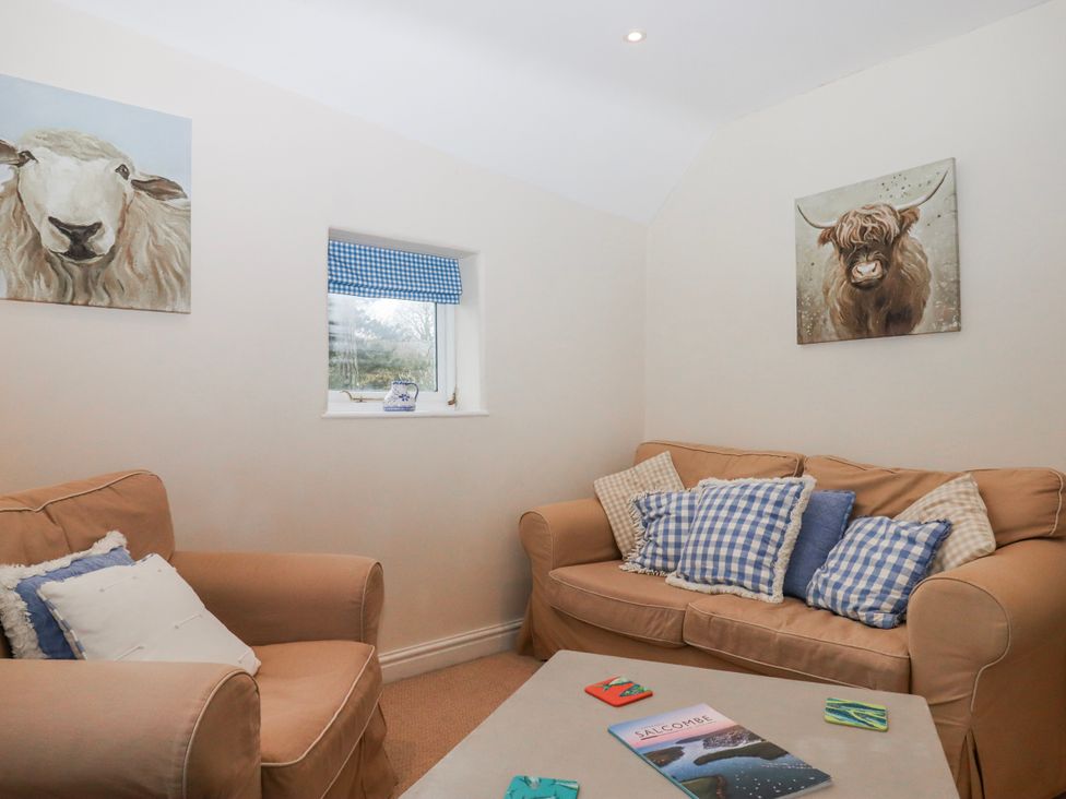 A snug with a sofa and coffee table at Yew Tree Cottage in Stoke Fleming