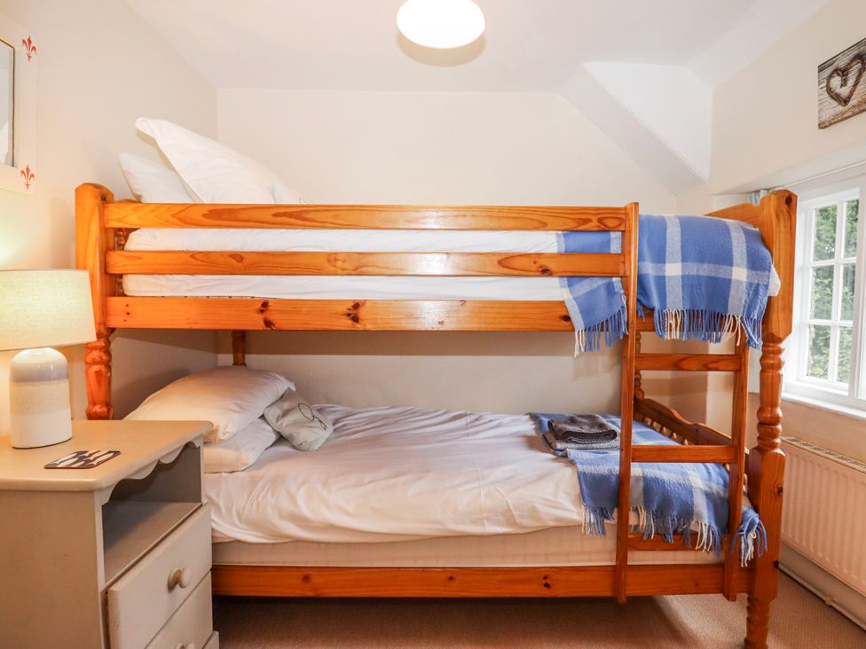 A bedroom with a bunk bed and a lamp at Yew Tree Cottage Stoke Fleming