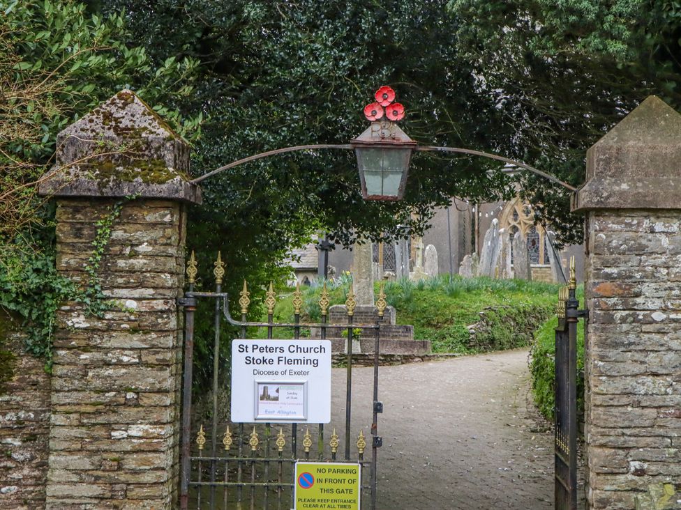 A gate with a sign and gravestones at St Peters Church in Stoke Fleming