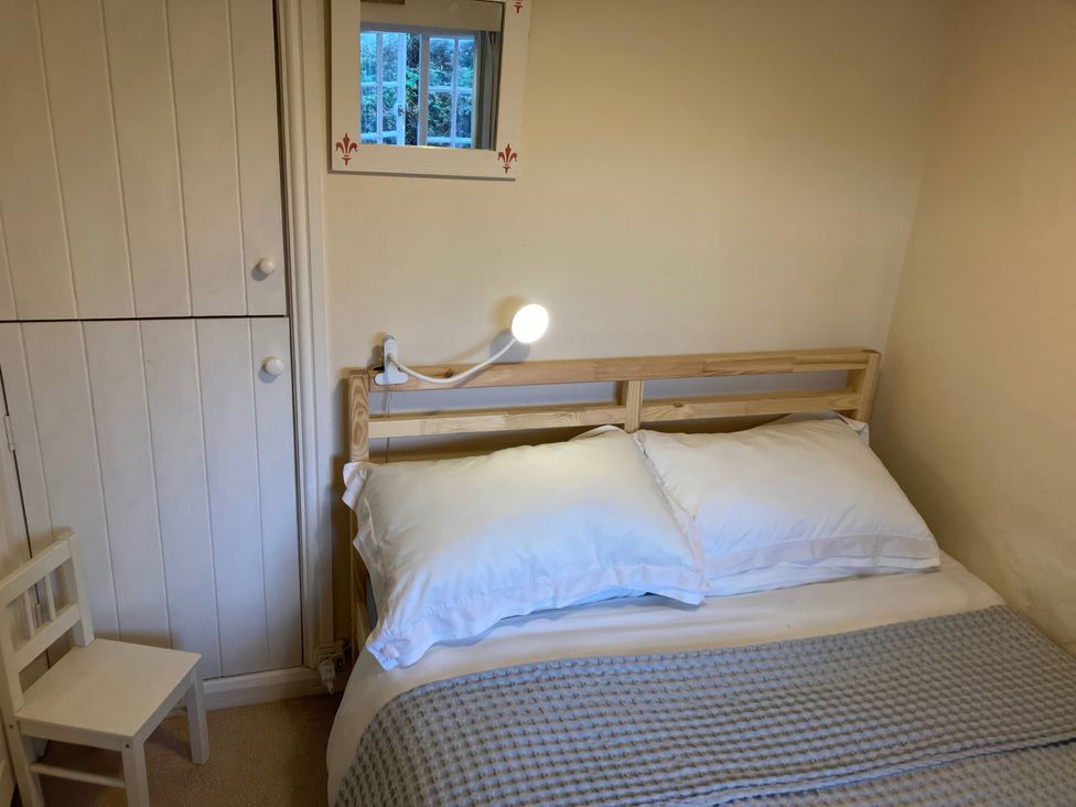 A bedroom with a bed and chair at Yew Tree Cottage in Stoke Fleming
