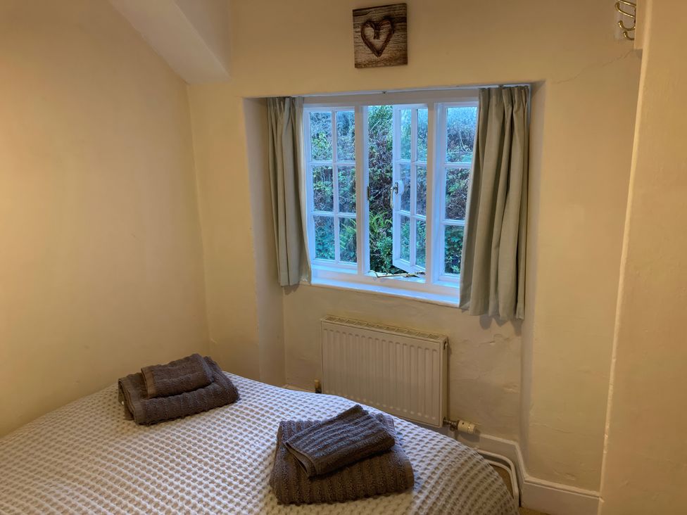 A bedroom with a bed and window at Yew Tree Cottage Stoke Fleming