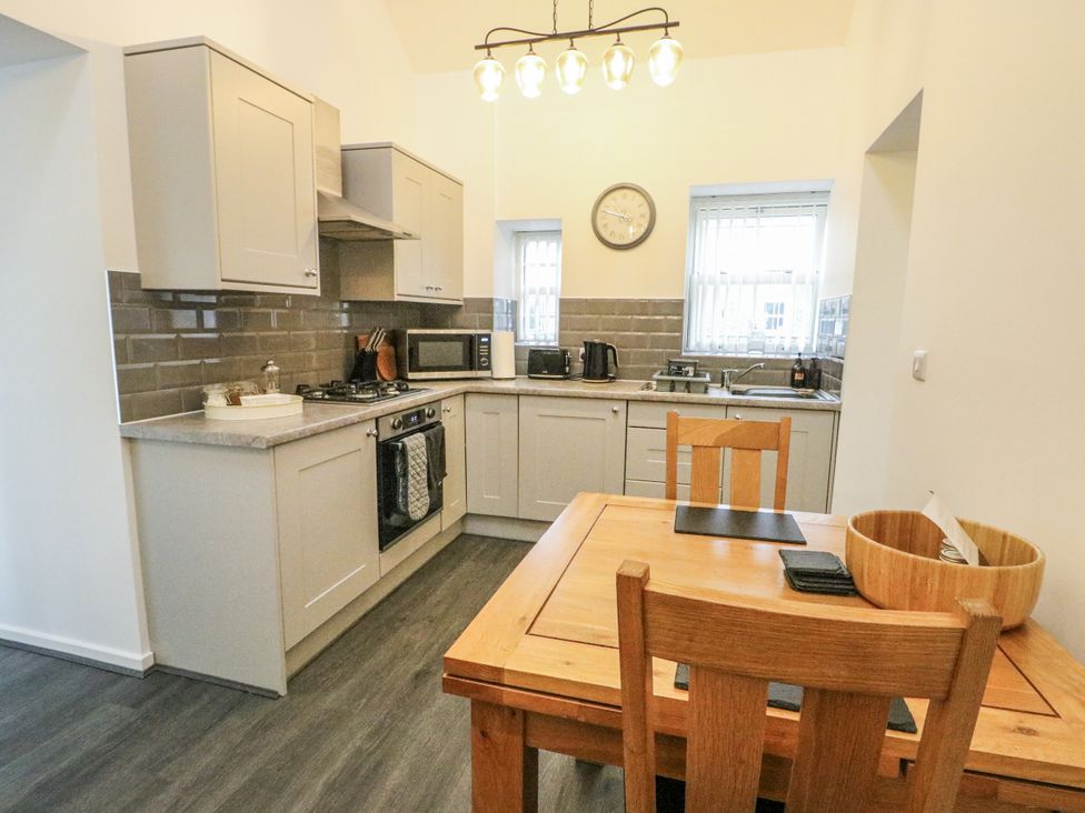 A kitchen with gray cabinets and a dining table at 2 Mountain View Talwrn near Llangefni