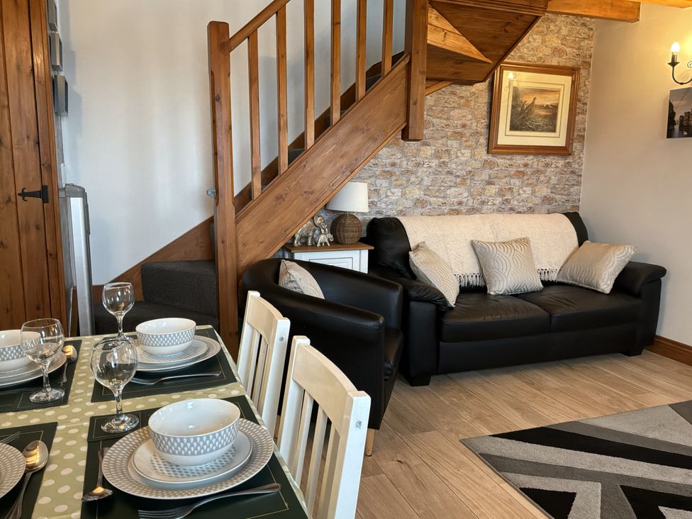 A living room with a sofa and dining area at Ysgubor Ddegwm Bach in Llanddona near Beaumaris