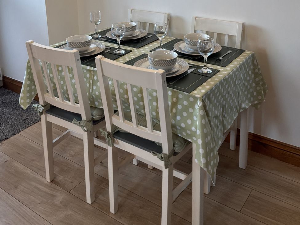 A dining room with a table set for four at Ysgubor Ddegwm Bach in Llanddona near Beaumaris