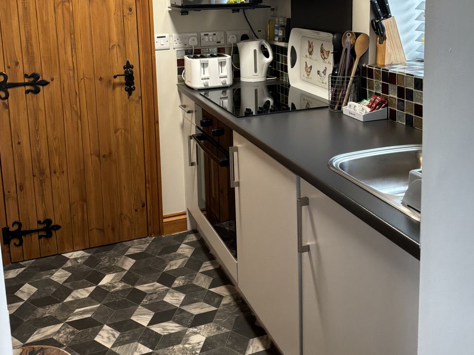 A kitchen with a countertop, sink, and appliances at Ysgubor Ddegwm Bach in Llanddona near Beaumaris