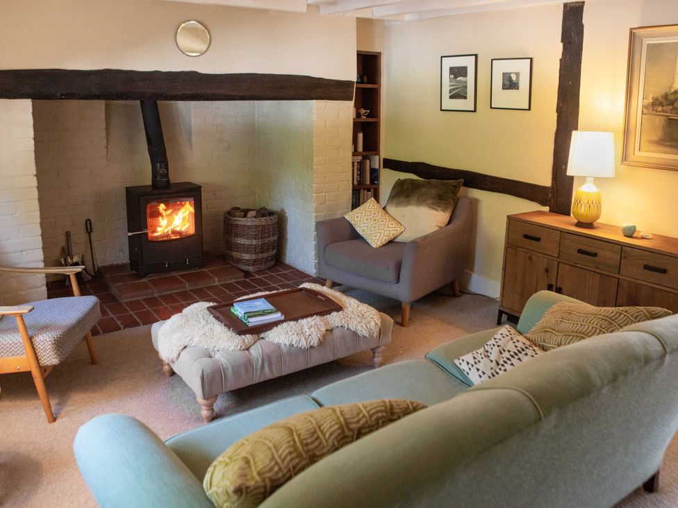 A living room with a fireplace and seating area at Newstead Farmhouse in East Chiltington near Lewes, Sussex