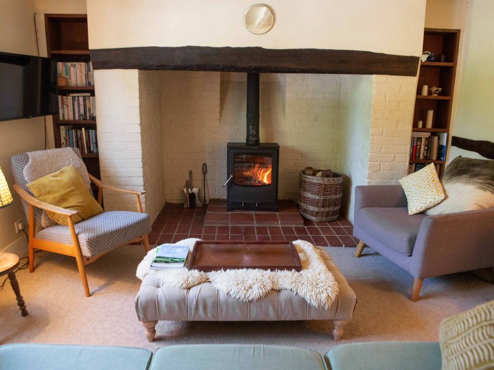 A living room with a fireplace and seating area at Newstead Farmhouse in East Chiltington near Lewes, Sussex