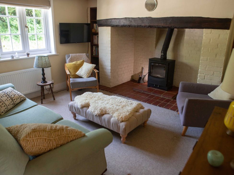 A living room with a fireplace and furniture at Newstead Farmhouse in East Chiltington near Lewes, Sussex