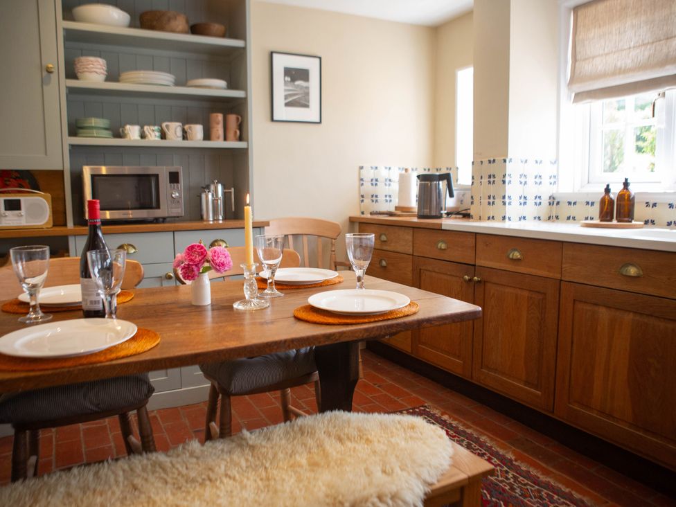 A dining room with a wooden table set for dinner at Newstead Farmhouse in East Chiltington near Lewes, Sussex