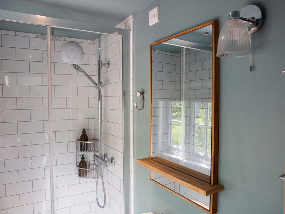 A shower with a mirror and shelf in the bathroom at Newstead Farmhouse in East Chiltington near Lewes, Sussex