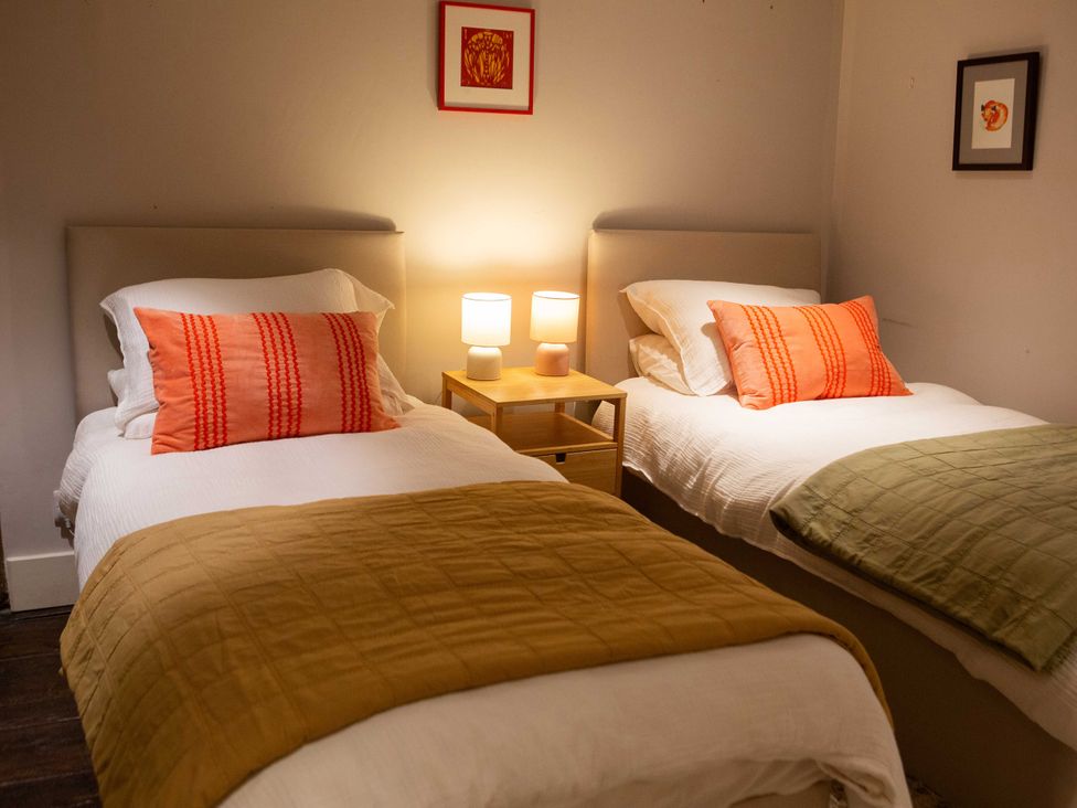 A bedroom with two beds and a nightstand at Newstead Farmhouse in East Chiltington near Lewes, Sussex