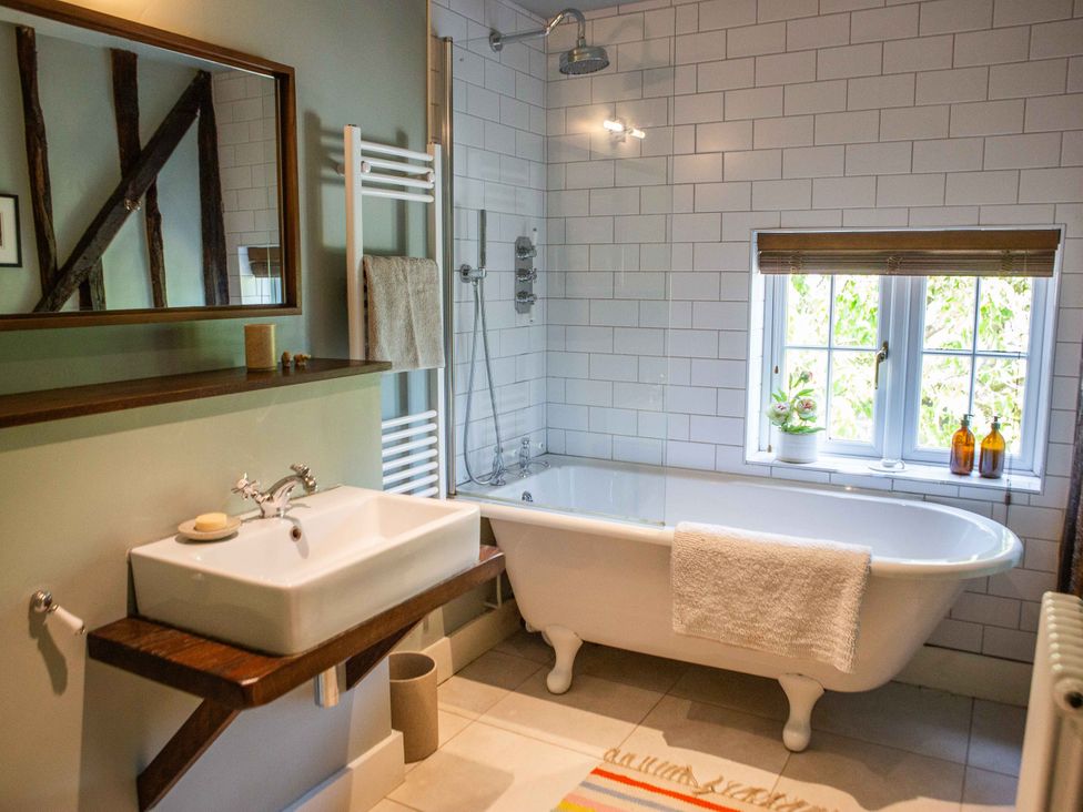 A bathroom with a bathtub, sink, and towel rail at Newstead Farmhouse in East Chiltington near Lewes, Sussex