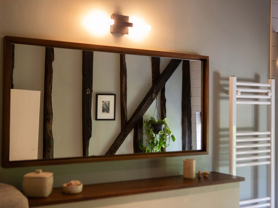 A bathroom with a mirror and shelf at Newstead Farmhouse in East Chiltington near Lewes, Sussex
