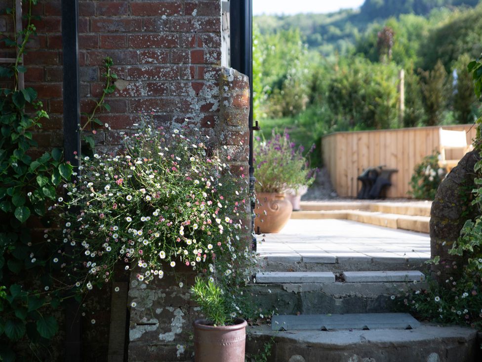 A garden with a brick wall and flower pots at Newstead Farmhouse East Chiltington near Lewes, Sussex