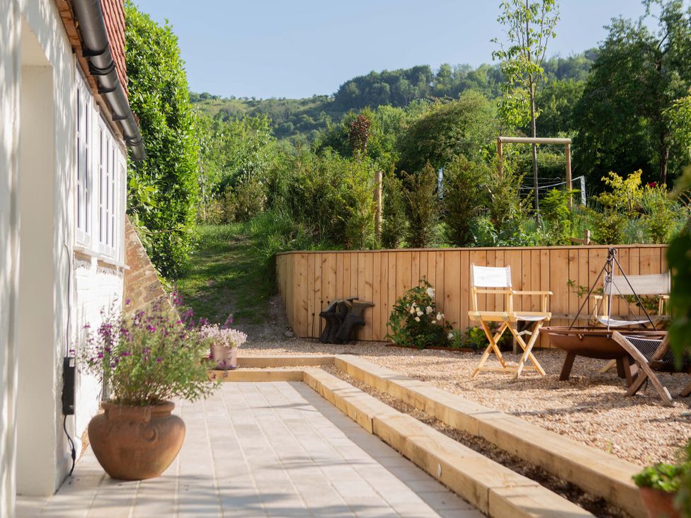 A garden with a pathway, chairs, and a fire pit at Newstead Farmhouse in East Chiltington near Lewes, Sussex