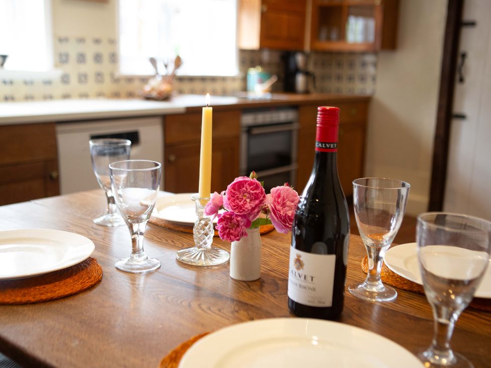 A dining table set with plates, a wine bottle, and flowers at Newstead Farmhouse in East Chiltington near Lewes, Sussex