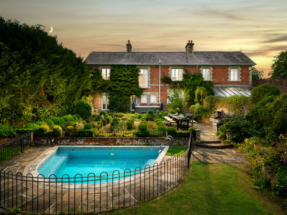 A garden with a swimming pool and a house at The Downwood in Blandford Forum