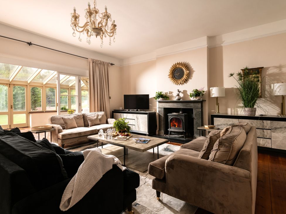 A living room with a chandelier and fireplace at The Downwood in Blandford Forum