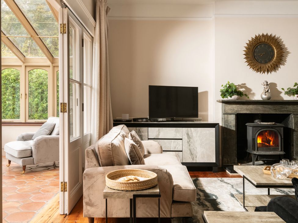 A living room with a sofa, television, and fireplace at The Downwood in Blandford Forum