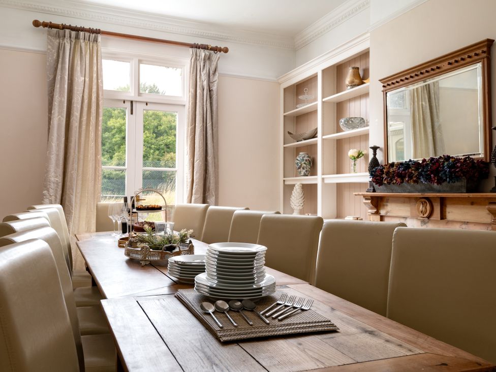 A dining room with a long table set for a meal at The Downwood in Blandford Forum
