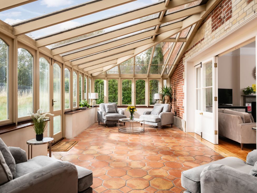 A conservatory with chairs and a table at The Downwood in Blandford Forum
