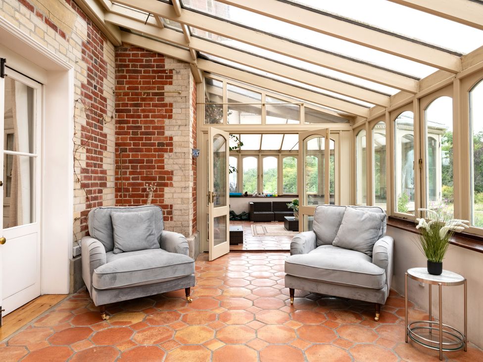 A conservatory with two sofas and a small table at The Downwood in Blandford Forum