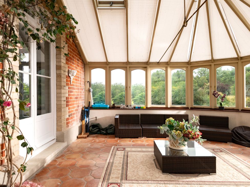 A conservatory with seating and a coffee table at The Downwood in Blandford Forum