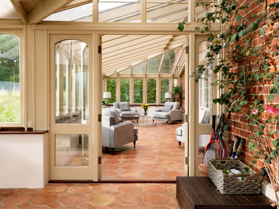 A conservatory with sofas and a table at The Downwood in Blandford Forum