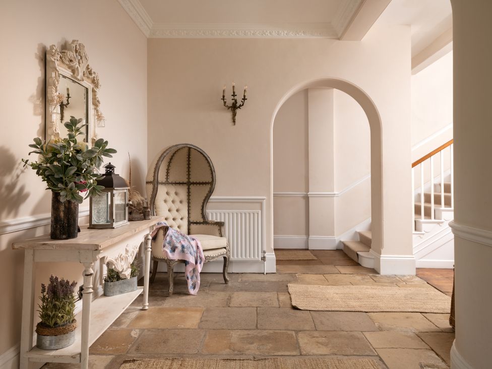 A hallway with a console table, chair, and mirror at The Downwood in Blandford Forum