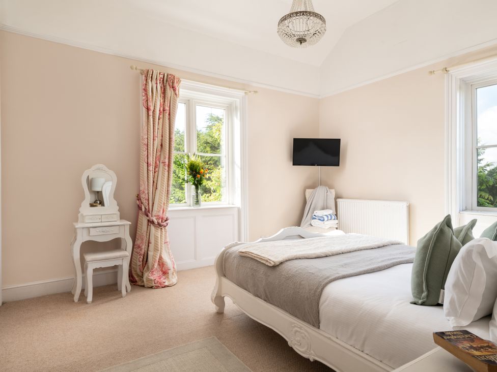 A bedroom with a bed and a mirror at The Downwood in Blandford Forum