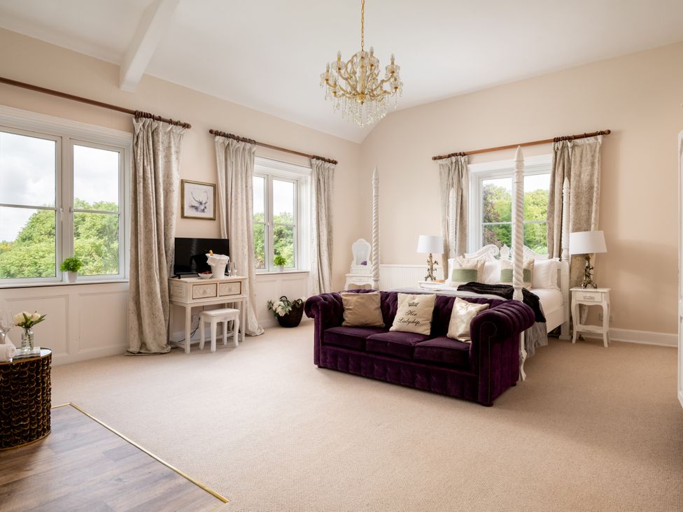 A bedroom with a purple sofa and a bed at The Downwood in Blandford Forum