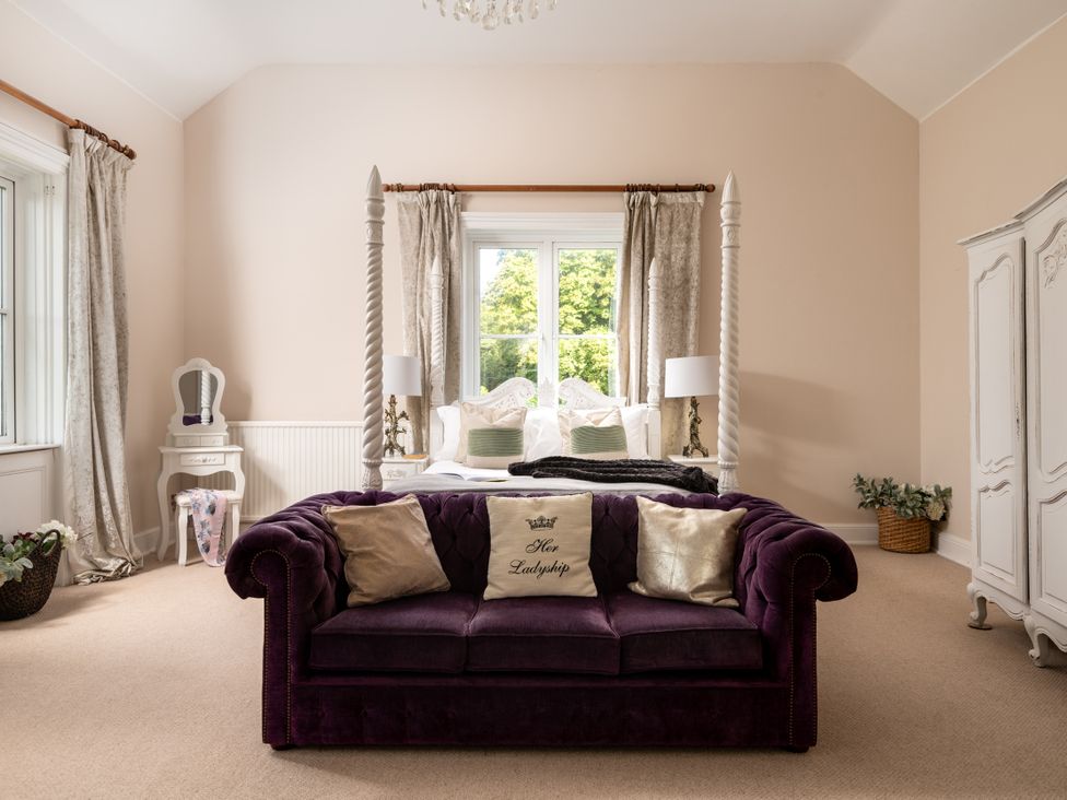 A bedroom with a purple sofa and a bed at The Downwood in Blandford Forum