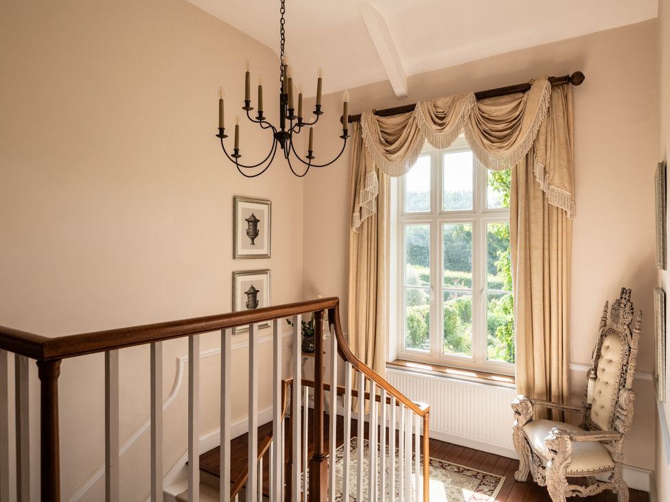 A staircase with a chandelier and a window at The Downwood in Blandford Forum