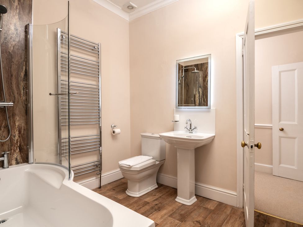 A bathroom with a bath tub, toilet, sink, and heated towel rail at The Downwood in Blandford Forum