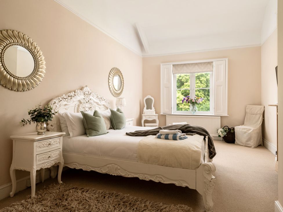 A bedroom with a bed, bedside table and window at The Downwood in Blandford Forum