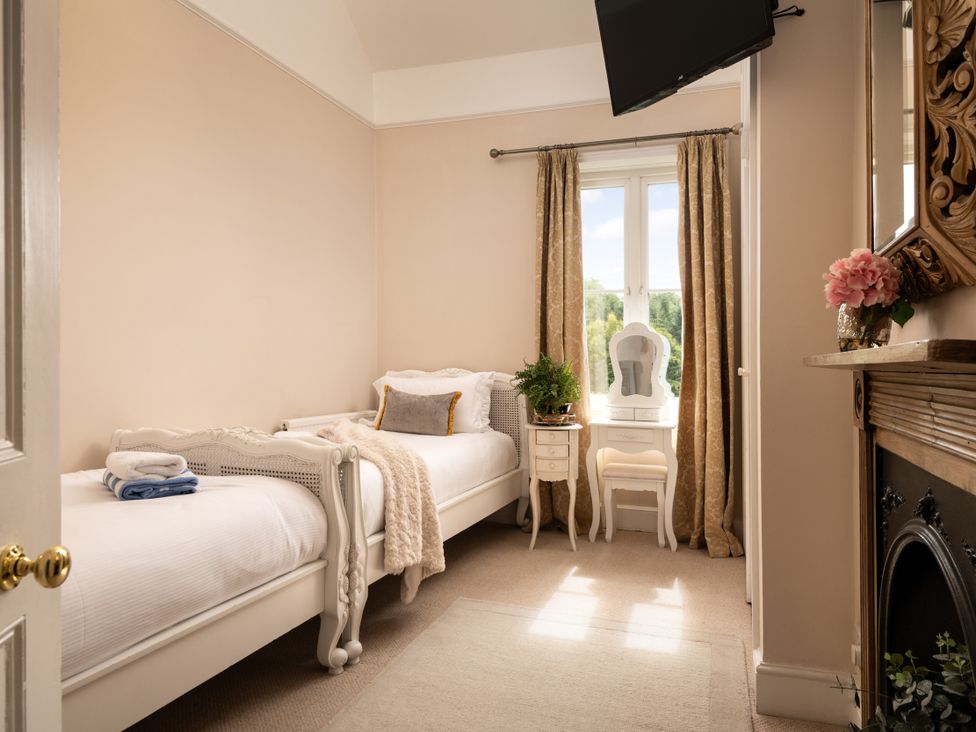 A bedroom with two beds and a mirror at The Downwood in Blandford Forum