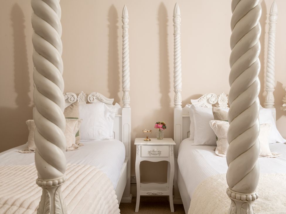 A bedroom with two four-poster beds and a bedside table at The Downwood in Blandford Forum