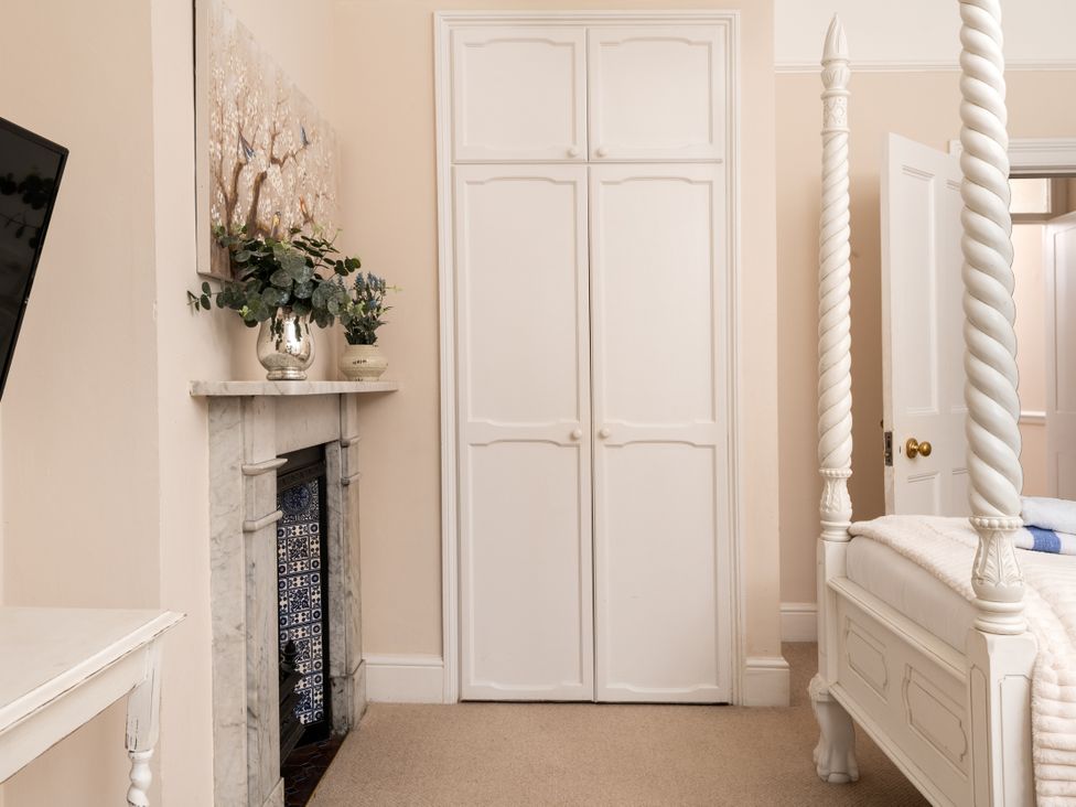 A bedroom with a four-poster bed and wardrobe at The Downwood in Blandford Forum