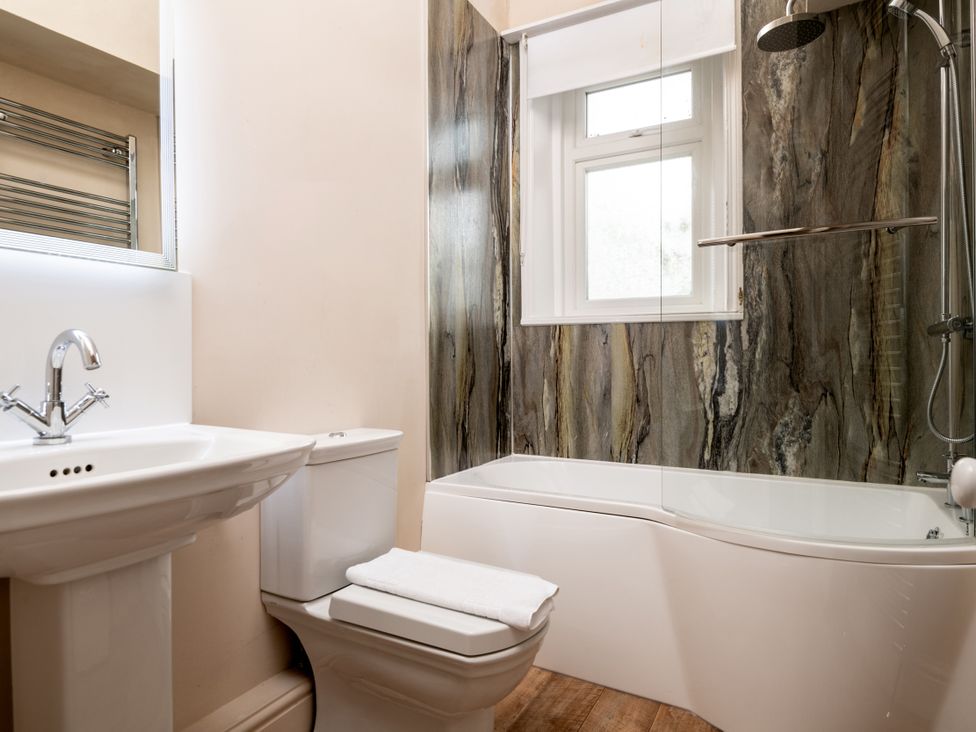 A bathroom with a bath tub, toilet, sink, and shower at The Downwood in Blandford Forum